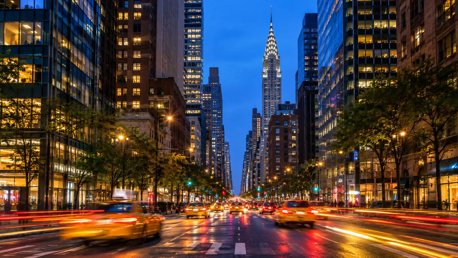 Gelbe Taxis auf einer Manhattan-Avenue in der Dämmerung unter leuchtenden Wolkenkratzern